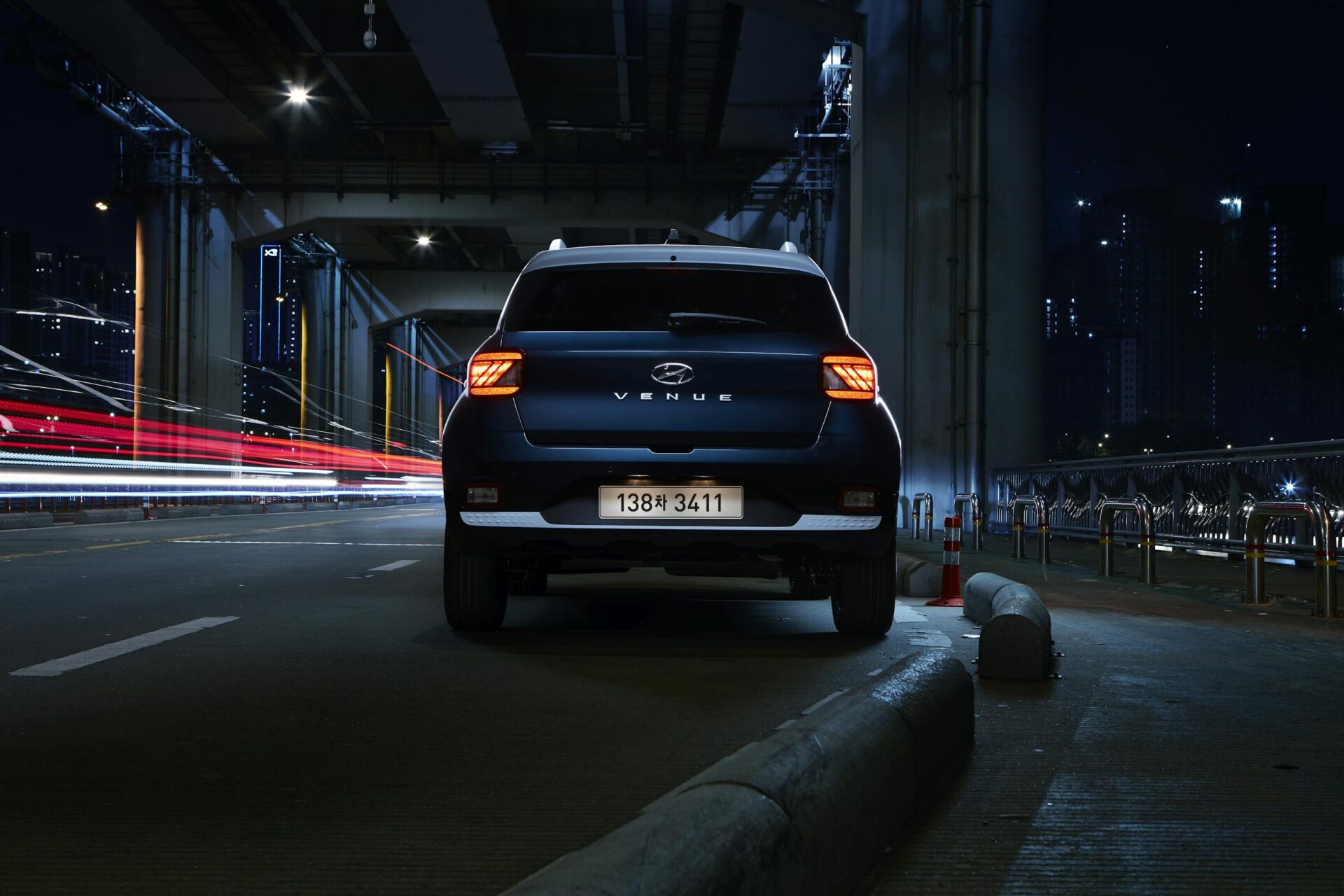 A Hyundai Venue SUV under a city bridge in Seoul at night with striking light trails.